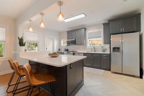 a kitchen with a sink a refrigerator and chairs