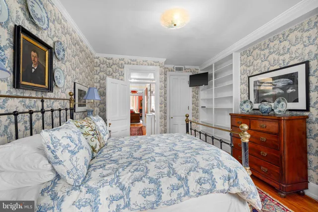 a bedroom with a bed dresser and wooden floor