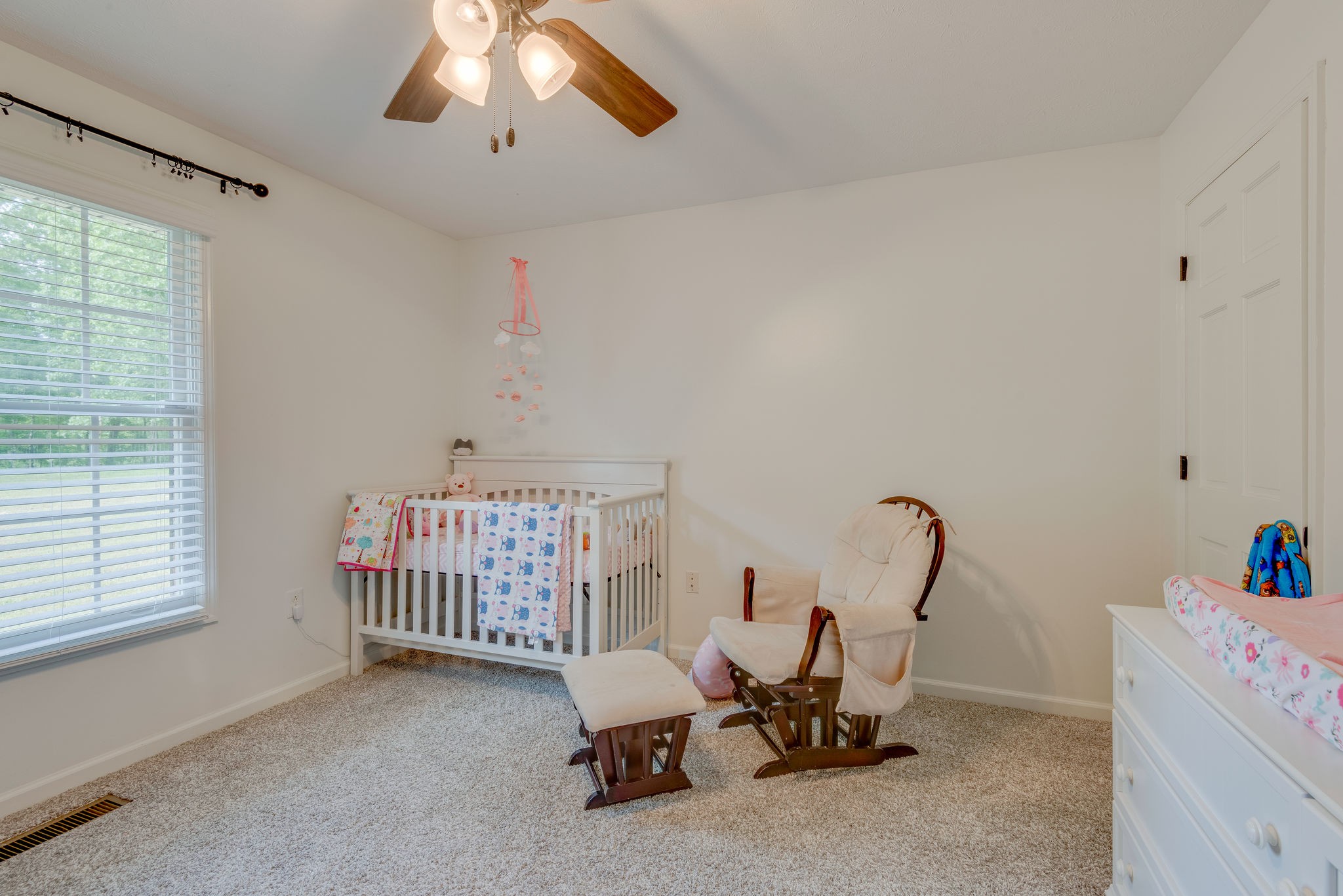 770 Iron Hill Road Burns, TN 37029 - Photo 23 of 28 a room with a baby crib a chandelier fan and a window