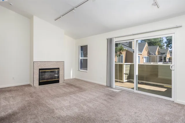 an empty room with floor to ceiling window and fireplace