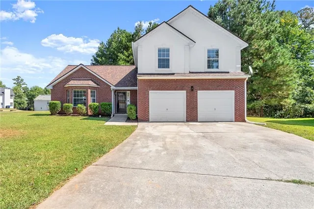 a view of a yard in front of a house with plants and large tree