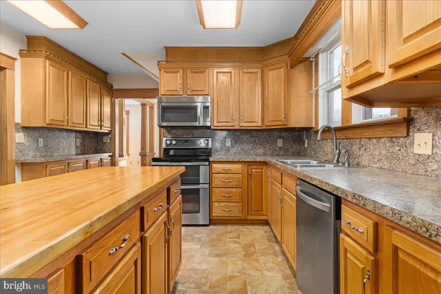 a kitchen with stainless steel appliances granite countertop a sink a stove cabinets counter space and a window