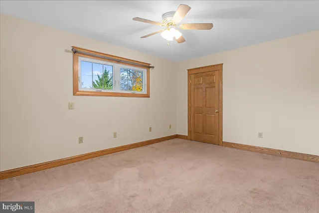an empty room with a window and a fan