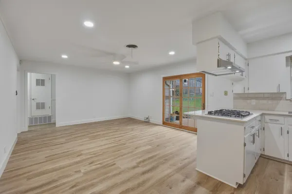 a view of kitchen with stainless steel appliances wooden floor and window