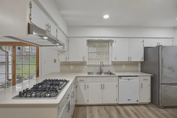 a view of kitchen with stainless steel appliances a sink and wooden floor
