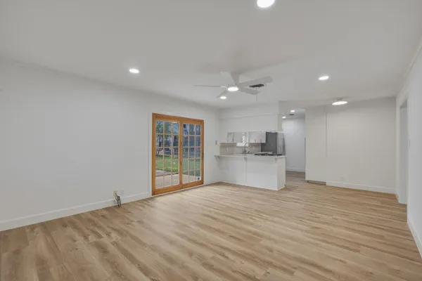 a view of an empty room with wooden floor and a window