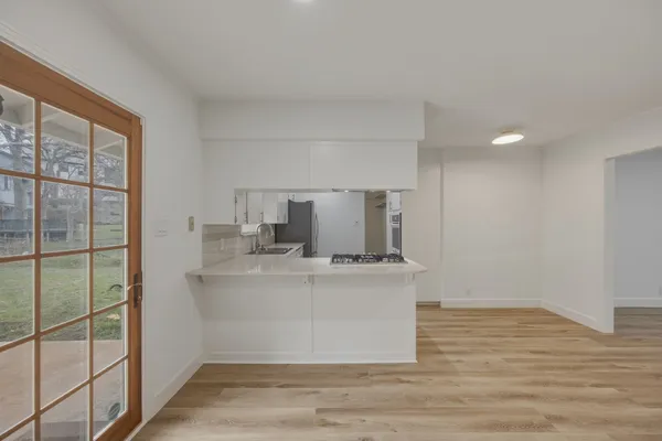 a view of kitchen with stainless steel appliances a sink and wooden floor