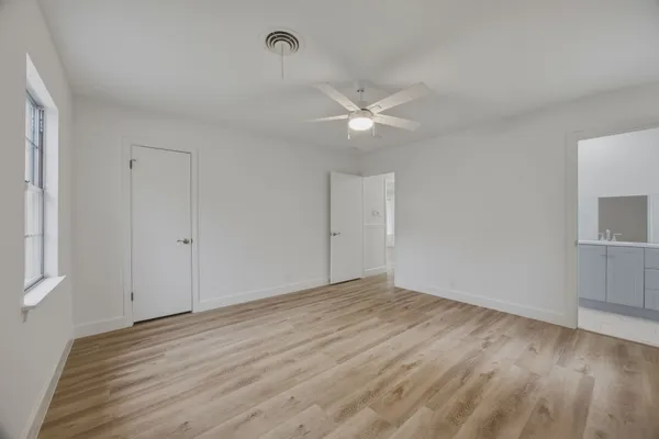 an empty room with wooden floor and ceiling fan