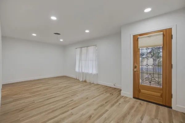 a view of an empty room with wooden floor and a window