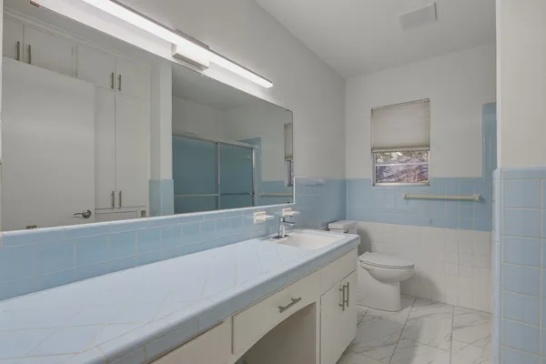 a bathroom with a granite countertop sink a toilet and a mirror