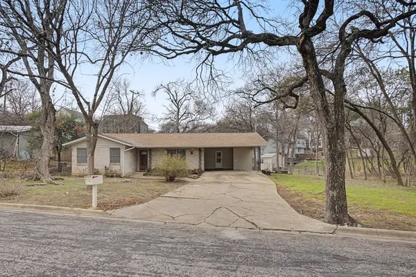 a front view of a house with garden and trees