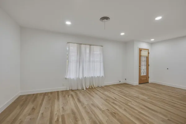 an empty room with wooden floor and windows