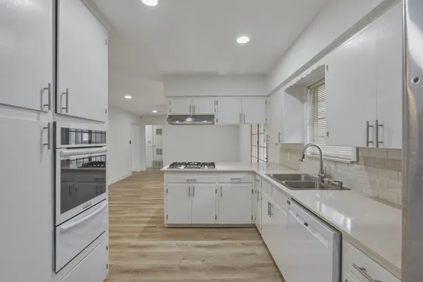 a large kitchen with granite countertop a sink and cabinets