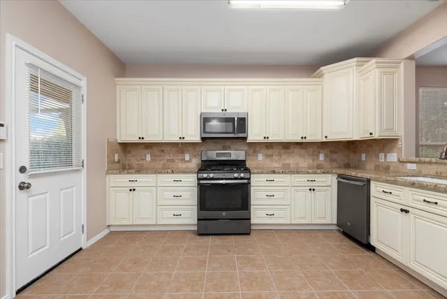a kitchen with granite countertop white cabinets and stainless steel appliances