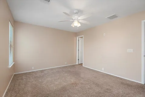 an empty room with a fan and a window