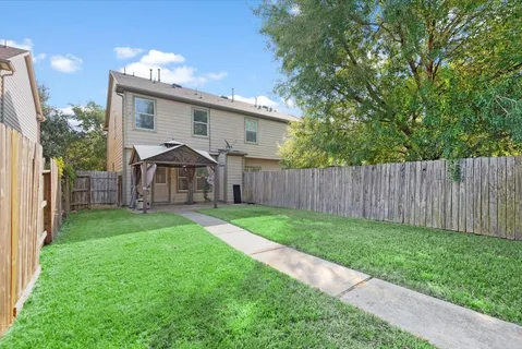a view of a house with backyard and a tree