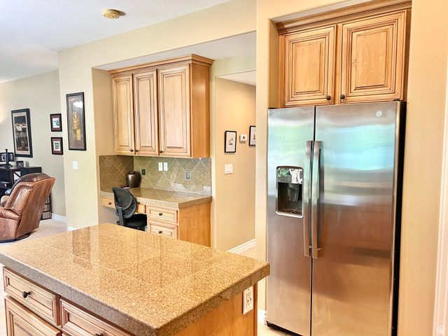 369 Culross Circle Tooele, UT 84074 - Photo 12 of 54 Kitchen island with a speckled granite countertop, integrated desk area, and wood-finish cabinetry