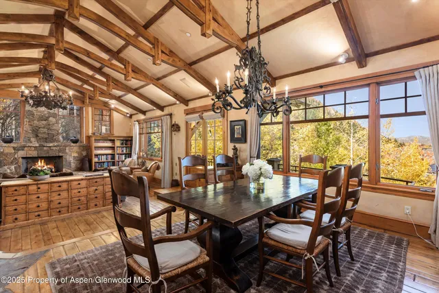 a view of a dining room with furniture a chandelier and large windows