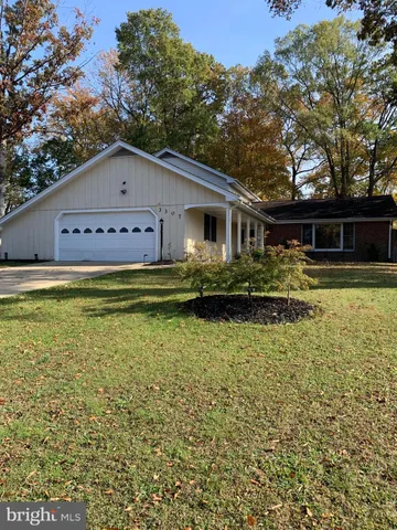 a front view of house with yard and trees in the background