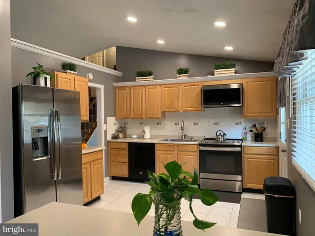 a kitchen with stainless steel appliances kitchen island granite countertop a refrigerator a sink dishwasher a stove a microwave oven with cabinets and wooden floor