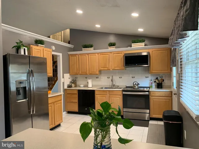 a kitchen with stainless steel appliances kitchen island granite countertop a refrigerator a sink a stove and cabinets