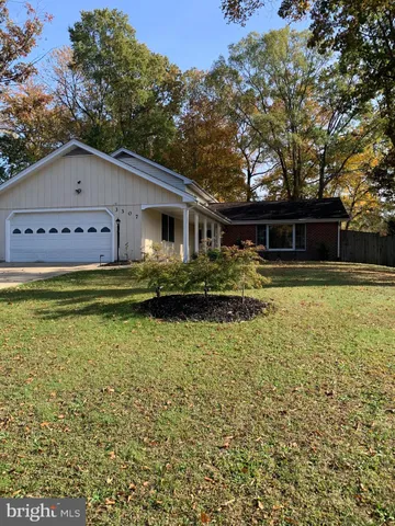 a front view of house with yard and trees in the background