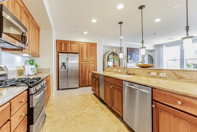a kitchen with stainless steel appliances granite countertop a sink a stove and a refrigerator