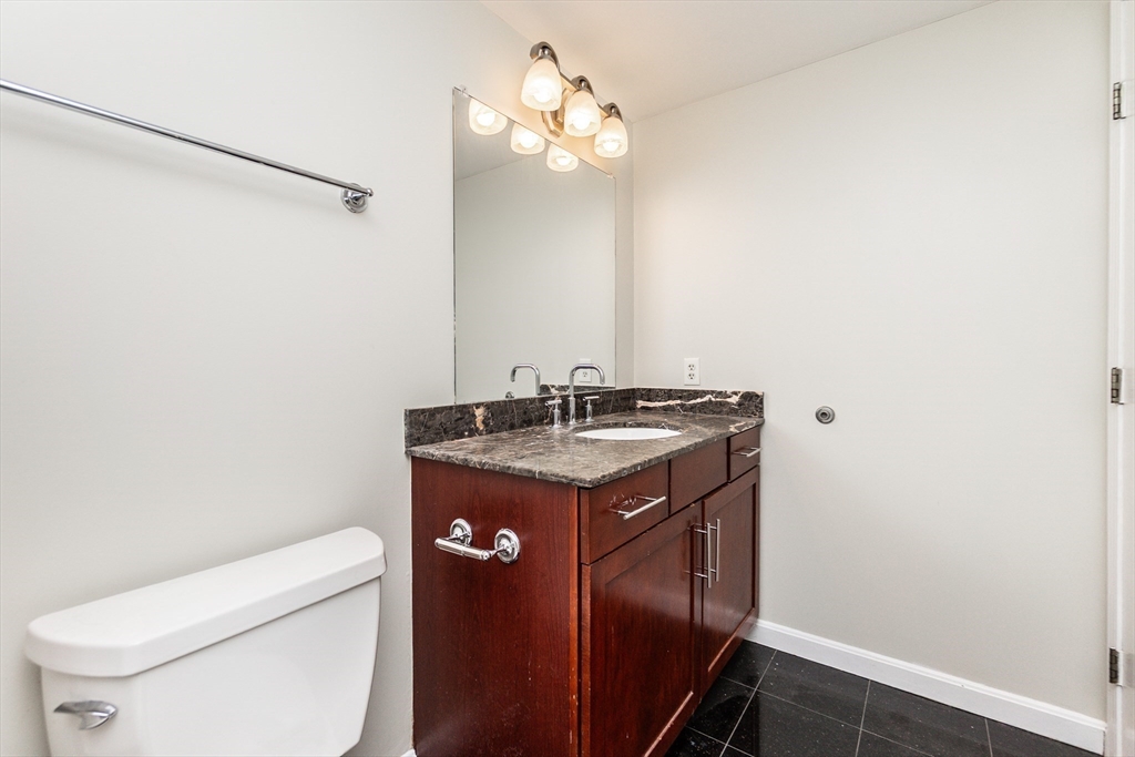 8-12 Museum Way, Unit 1224 Cambridge, MA 02141 - Photo 9 of 18 a bathroom with a granite countertop sink toilet and a mirror