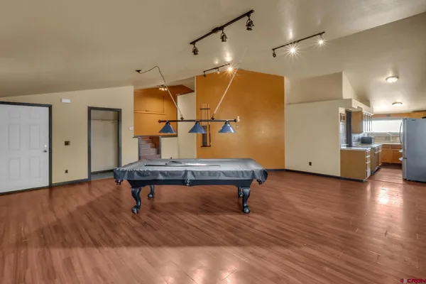 a living room with wooden floor pool table and chairs