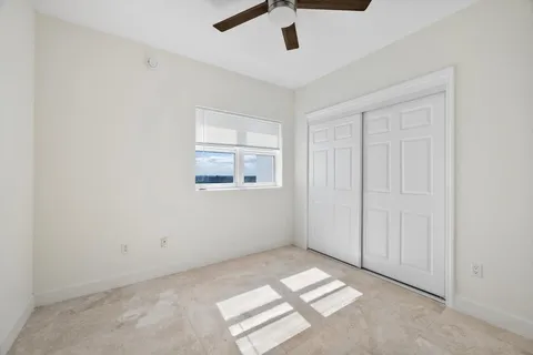 an empty room with windows and ceiling fan