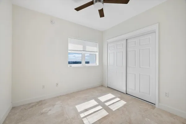an empty room with windows and ceiling fan