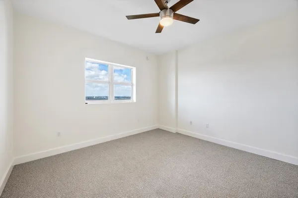 an empty room with a window and a fan