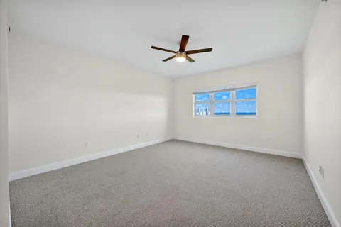 an empty room with a window and a ceiling fan