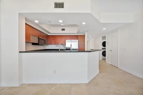 a view of a kitchen with kitchen island a sink stainless steel appliances and a counter top space