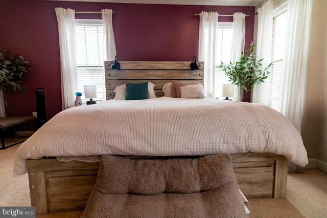 a bed sitting in a bedroom next to a window and a mirror