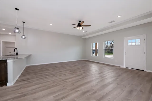a view of an empty room with a window and wooden floor