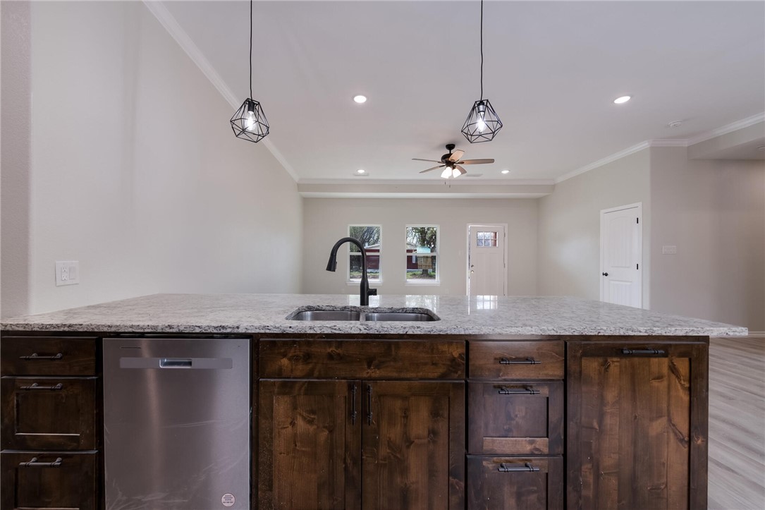 402 F Street Meridian, TX 76665 - Photo 19 of 32 a kitchen with a granite countertop kitchen island a sink and cabinets