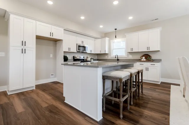 a kitchen with kitchen island granite countertop wooden floors and white stainless steel appliances