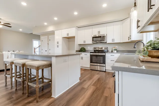 a kitchen with stainless steel appliances granite countertop a stove top oven a sink a dining table and chairs with wooden floor