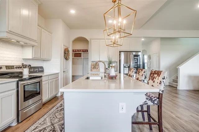 a kitchen with stainless steel appliances a table chairs and chandelier
