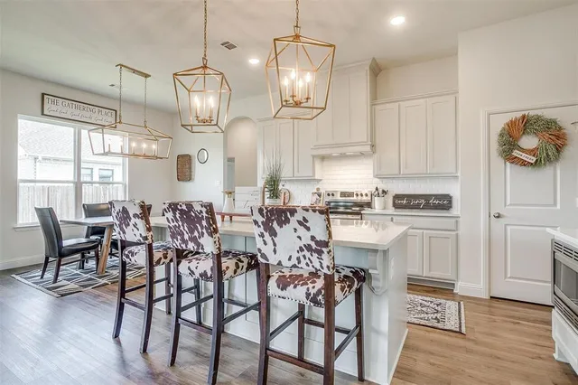 a kitchen with stainless steel appliances kitchen island wooden floors and white cabinets