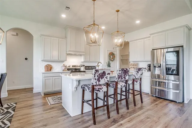 a kitchen with stainless steel appliances a dining table chairs stove and refrigerator