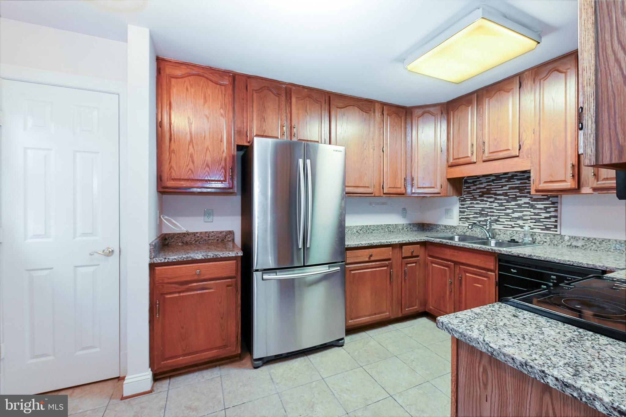 11223 Watermill Lane Silver Spring, MD 20902 - Photo 20 of 39 a kitchen with granite countertop wooden cabinets a refrigerator and a sink