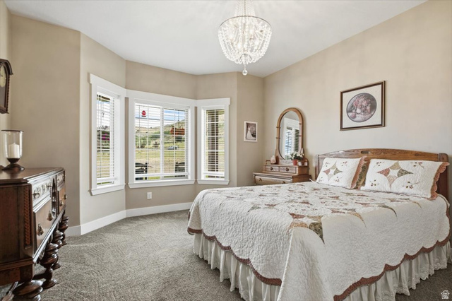 3123 East Riverdale Road Preston, ID 83263 - Photo 17 of 52 Bay window with white blinds, neutral wall paint, textured carpeting, and a crystal chandelier