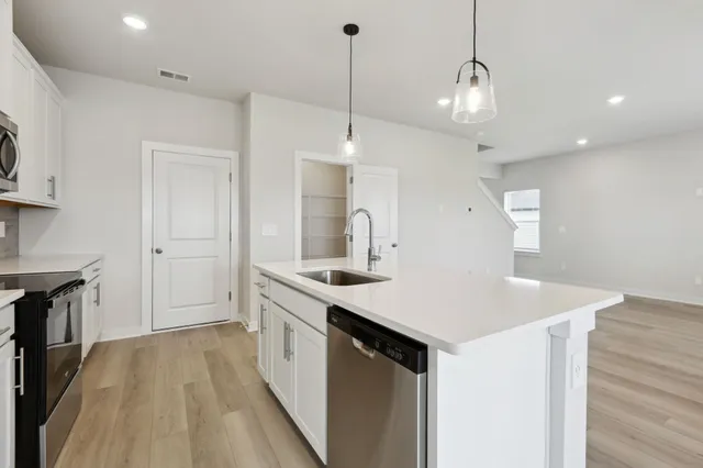 a kitchen with a sink a center island a stove and a wooden floor