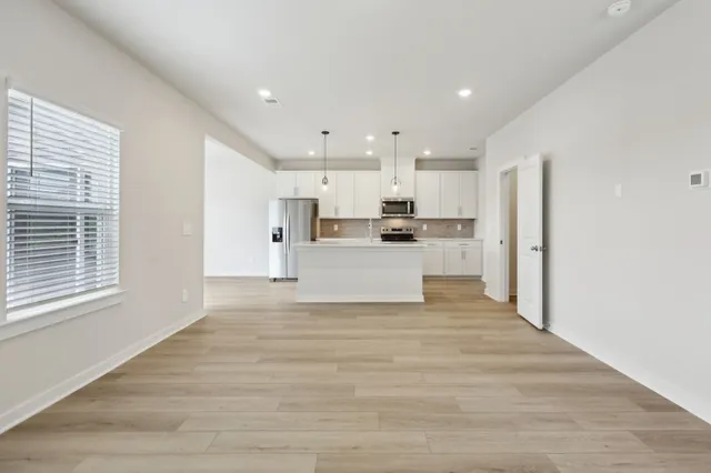 a view of kitchen with kitchen island wooden floors appliances and cabinets