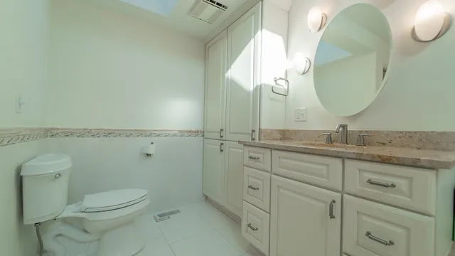 a spacious bathroom with a granite countertop sink a toilet and a mirror