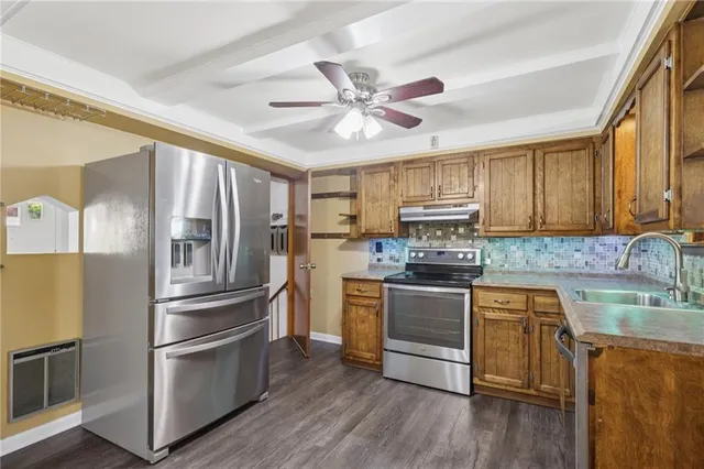 a kitchen with stainless steel appliances granite countertop a refrigerator a stove top oven a sink and dishwasher with wooden floor