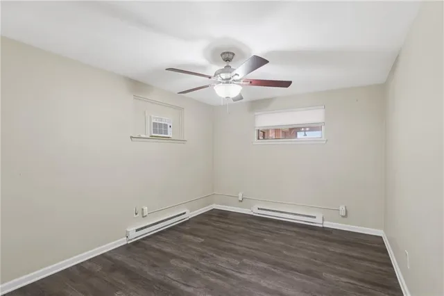 an empty room with wooden floor and ceiling fan