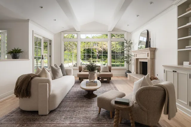 a living room with furniture fireplace and large windows